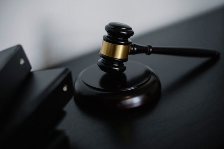 High angle of shiny wooden ceremonial mallet with golden detail placed on judge tale near documents folders