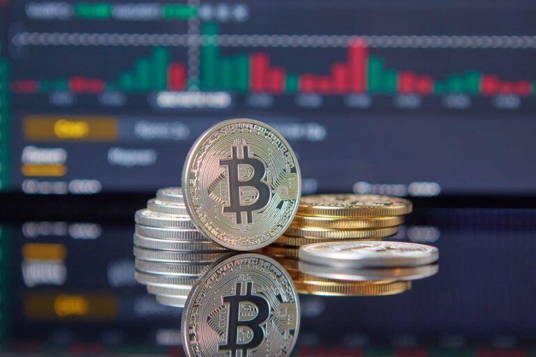 Close-up of Bitcoin coins on reflective surface with financial trading chart, symbolizing cryptocurrency market dynamics.